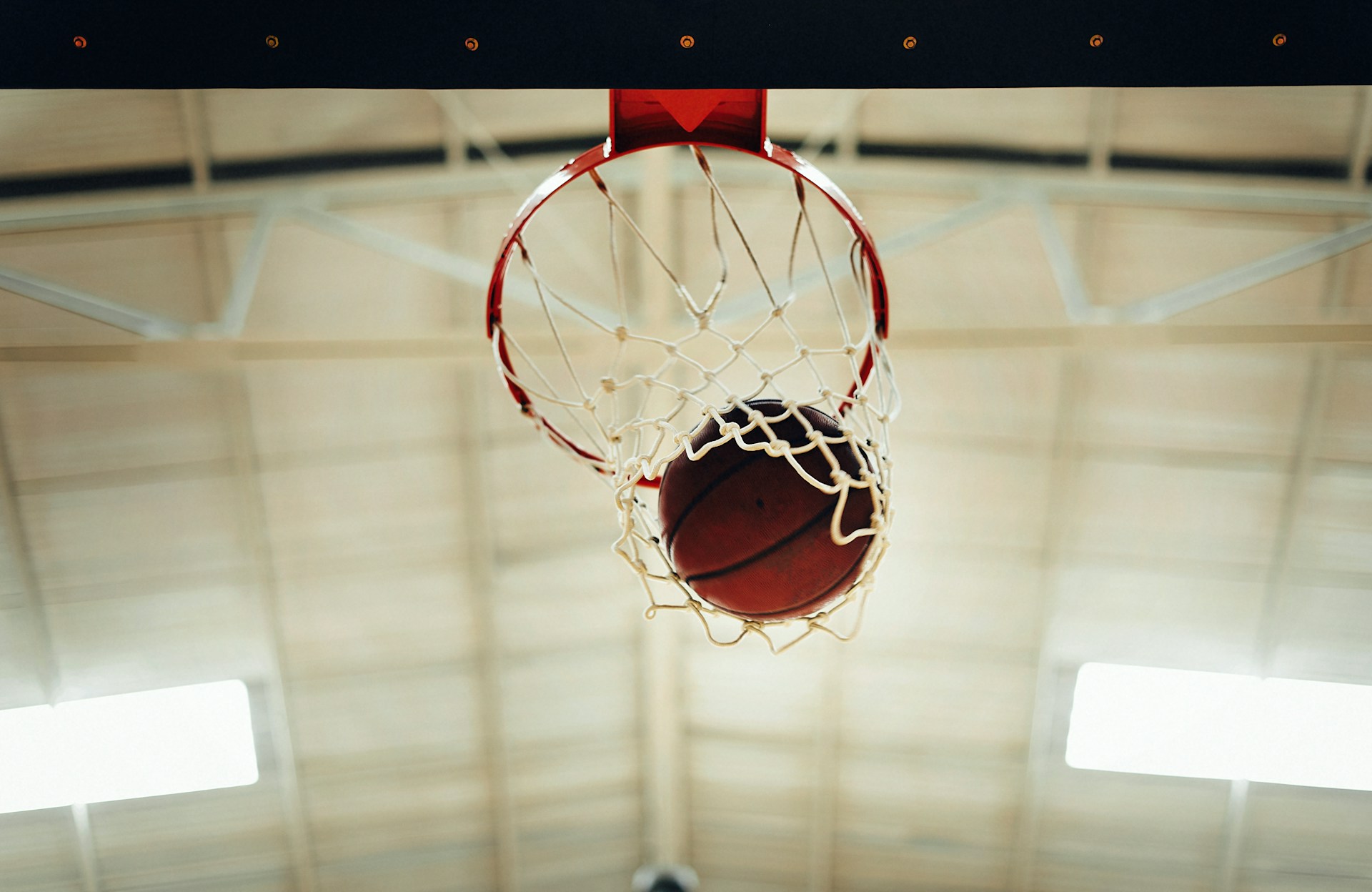 a low angle shot of a basketball going through a basketball hoop