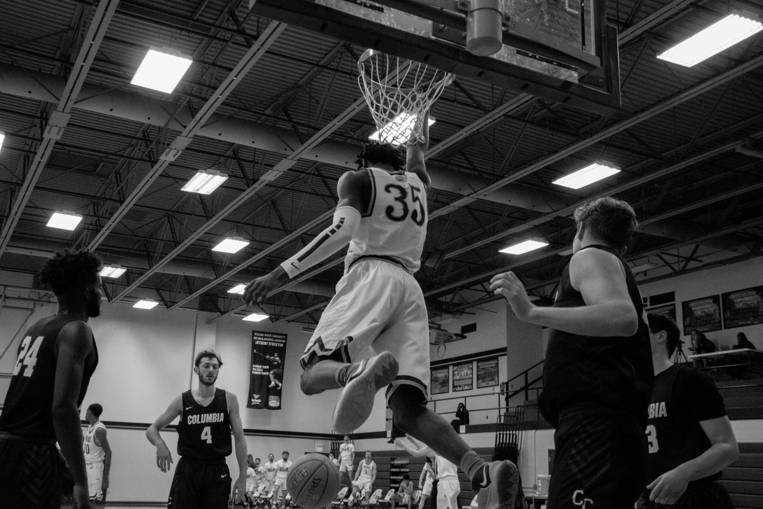 a black and white photo of a college basketball player dunking